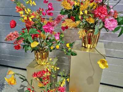 Artificial flowers in gold vases on plinths